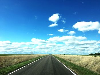 Road by landscape against blue sky