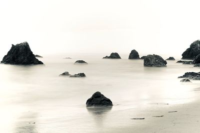Rocks in sea against clear sky