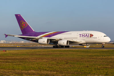 Airplane on airport runway against sky