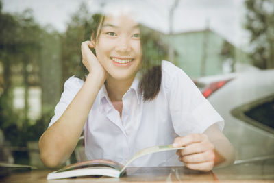 Portrait of smiling young woman reading book