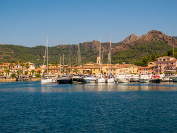 Sailboats moored at harbor against sky in city