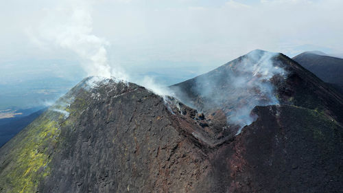 Crater etna top view from above in a panoramic aerial photo with sulphure and smoke at degassation