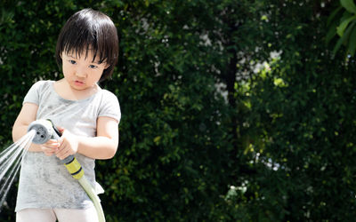 Full length of cute boy holding plants