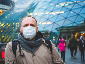 Adult european man wearing a mask outdoor near shopping center in a city