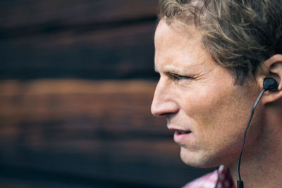 Man wearing hands-free device outside log cabin