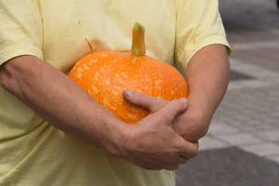 Midsection of man holding orange fruit