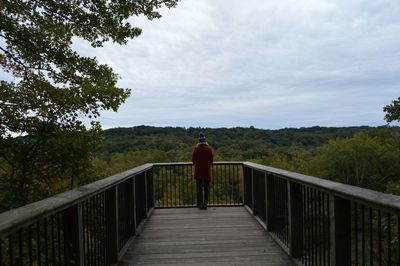 Footbridge over river against cloudy sky