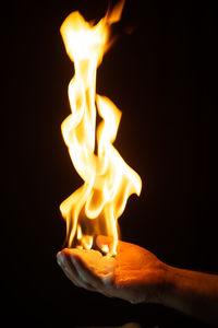 Close-up of burning candles against black background