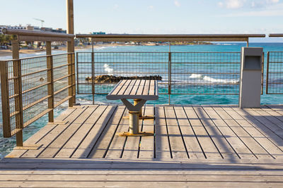 Empty chairs by swimming pool against sky