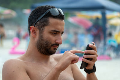 Portrait of young man using mobile phone on the beach