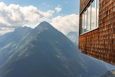 The wall of the building with windows is covered with wooden shingles and a view of the mountain