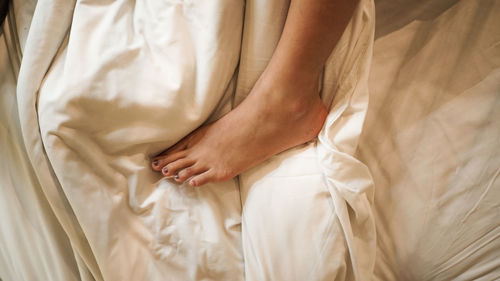 Low section of woman relaxing on bed