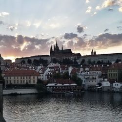 Town by river against cloudy sky