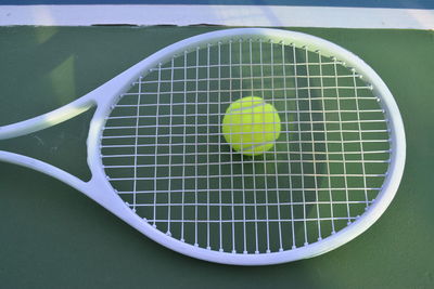 Directly above shot of ball on tennis racket at sports court