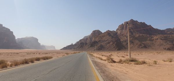 Road amidst desert against clear sky