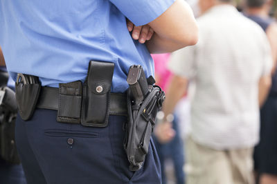 Midsection of police officer with handgun and handcuffs