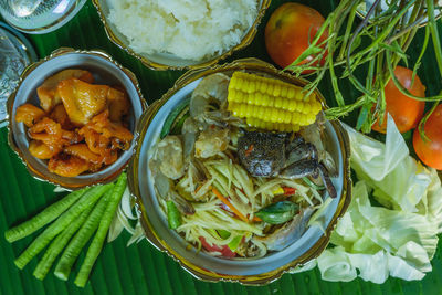 High angle view of papaya salad or som tam and sticky rice and grilled chicken.