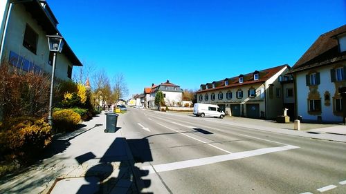 Road by buildings against sky in city