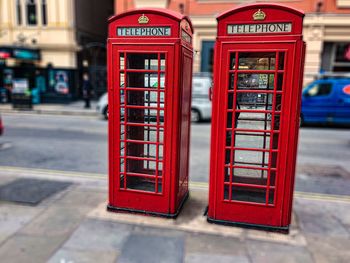 Red telephone booth on sidewalk in city