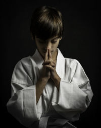 Boy standing against black background