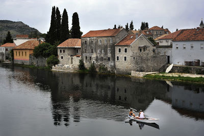 Houses by river against sky