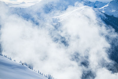 Skier amongst clouds and mountains in british columbia canada