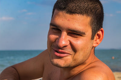 Close-up portrait of young man against sea