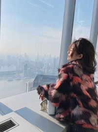 Woman looking through window in city