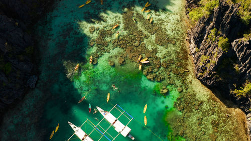 Tourist boats over tropical lagoon and coral reef, aerial view. el nido, philippines, palawan. 
