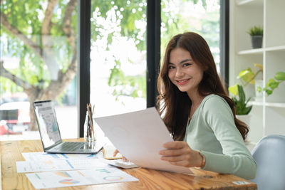 Portrait of young woman using laptop at office