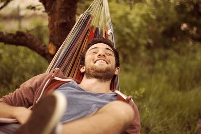 Close-up of a smiling young man in hammock outdoors