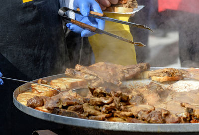 Midsection of chef preparing meat dish in large pot with plate. traditional croatian dish kotlovina