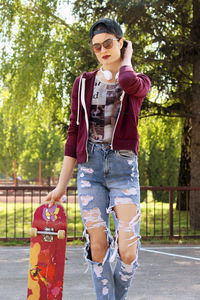 Young woman wearing sunglasses standing against trees