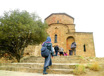 Rear view of people walking in front of historic building