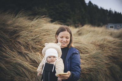 A woman with an infant is looking at a smartphone