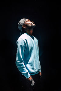 Young man looking away over black background