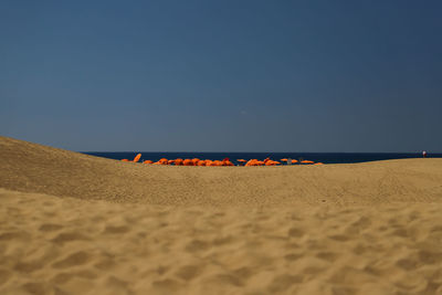 Deck chairs on beach against clear sky