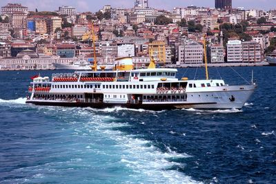 Passenger ship sailing in river against buildings on sunny day