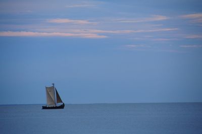 Sailboat sailing in sea against sky during sunset