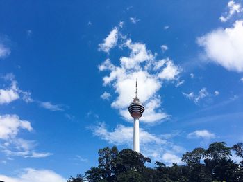 Low angle view of communications tower against cloudy sky