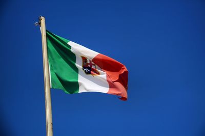 Low angle view of flag against clear blue sky