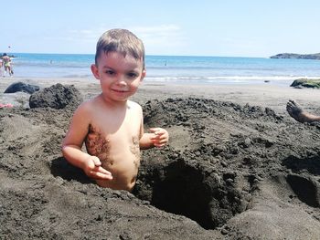 Portrait of cute boy playing in sand at beach