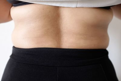 Midsection of woman standing against white background