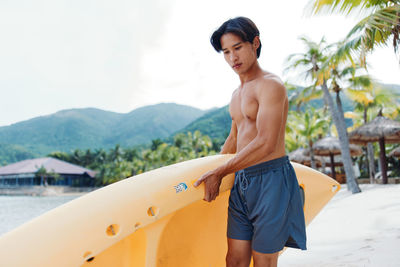 Full length of shirtless young man exercising at beach