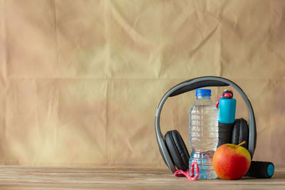 Close-up of apples in jar on table against wall