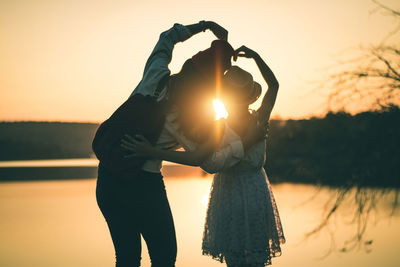 Silhouette couple standing against sun during sunset