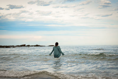 Rear view of man on beach against sky