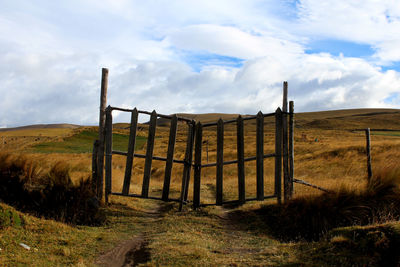 Wooden fence on field against sky