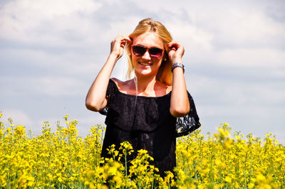 Portrait of smiling young woman wearing sunglasses on oilseed rape field