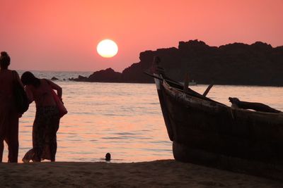 Women by boat at beach against sky